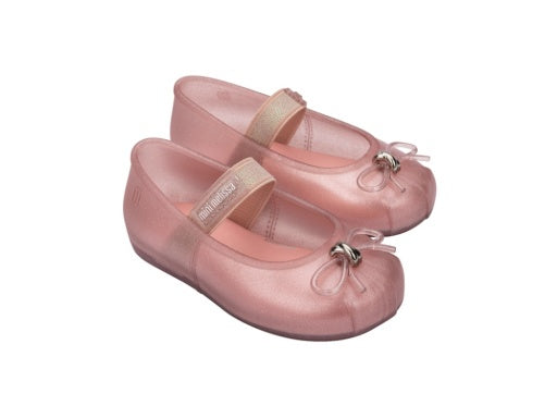 Pair of glittery pink Mini Melissa Mary Jane jelly flats with a gold strap featuring 'mini melissa' text and a clear bow with silver hardware.