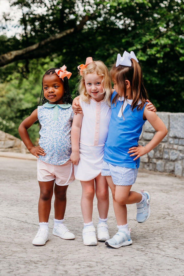 Three children in matching casual outfits standing arm-in-arm outdoors