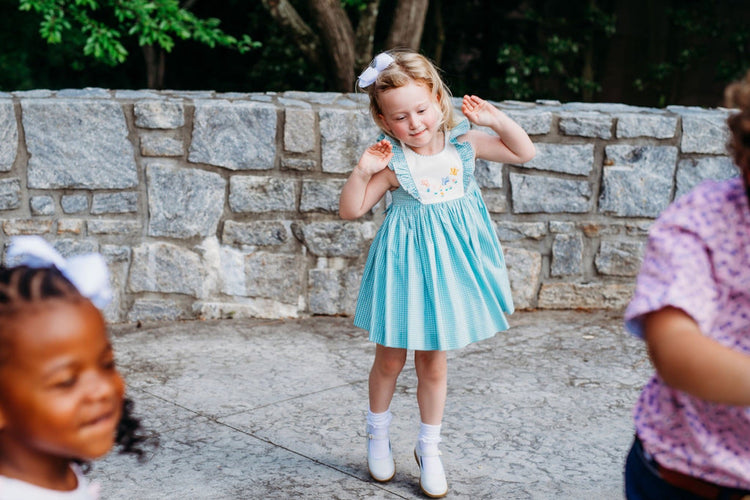 Girl in a smocked dress spinning in white dress shoes