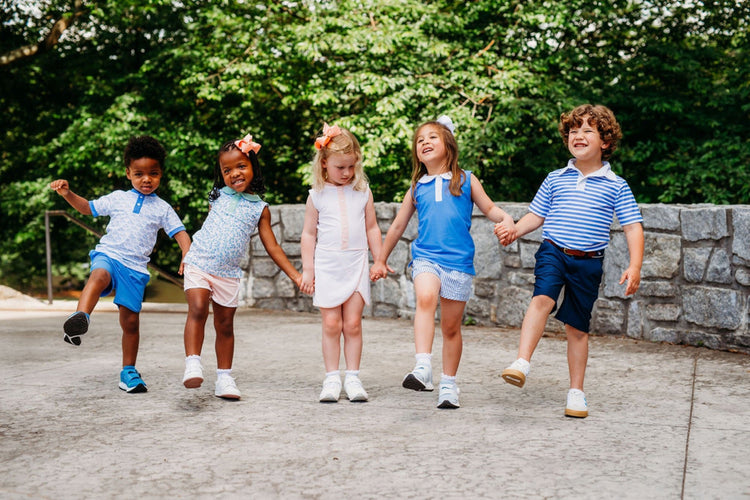 Five children running hand-in-hand outdoors