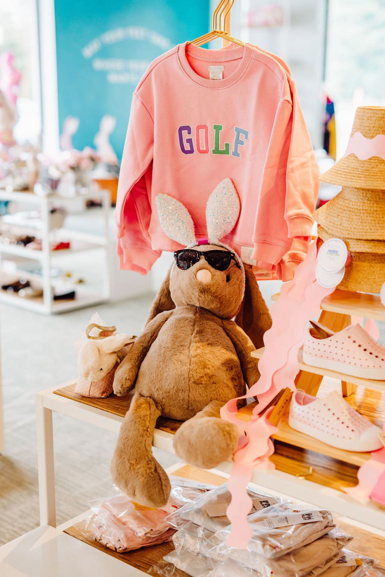 Plush bunny wearing sunglasses with Sprong merch and apparel display