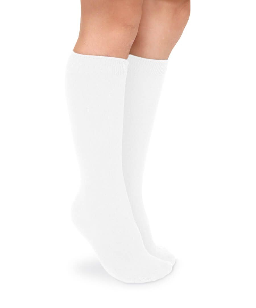 Child's legs wearing smooth white cotton knee socks with ribbed cuffs, standing on a white background.