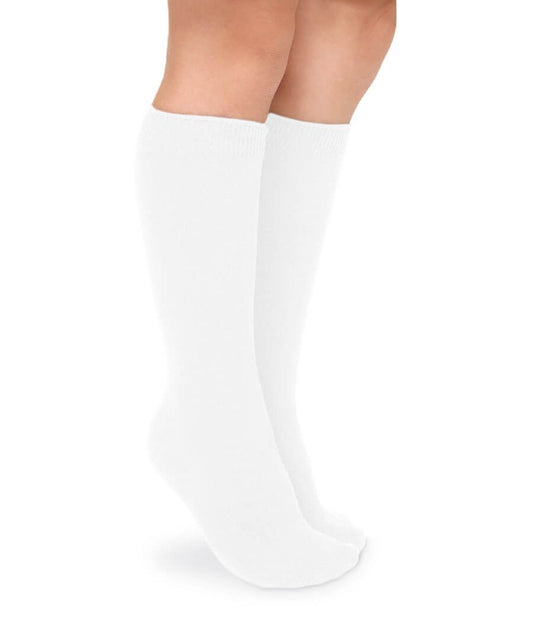 Child's legs wearing smooth white cotton knee socks with ribbed cuffs, standing on a white background.
