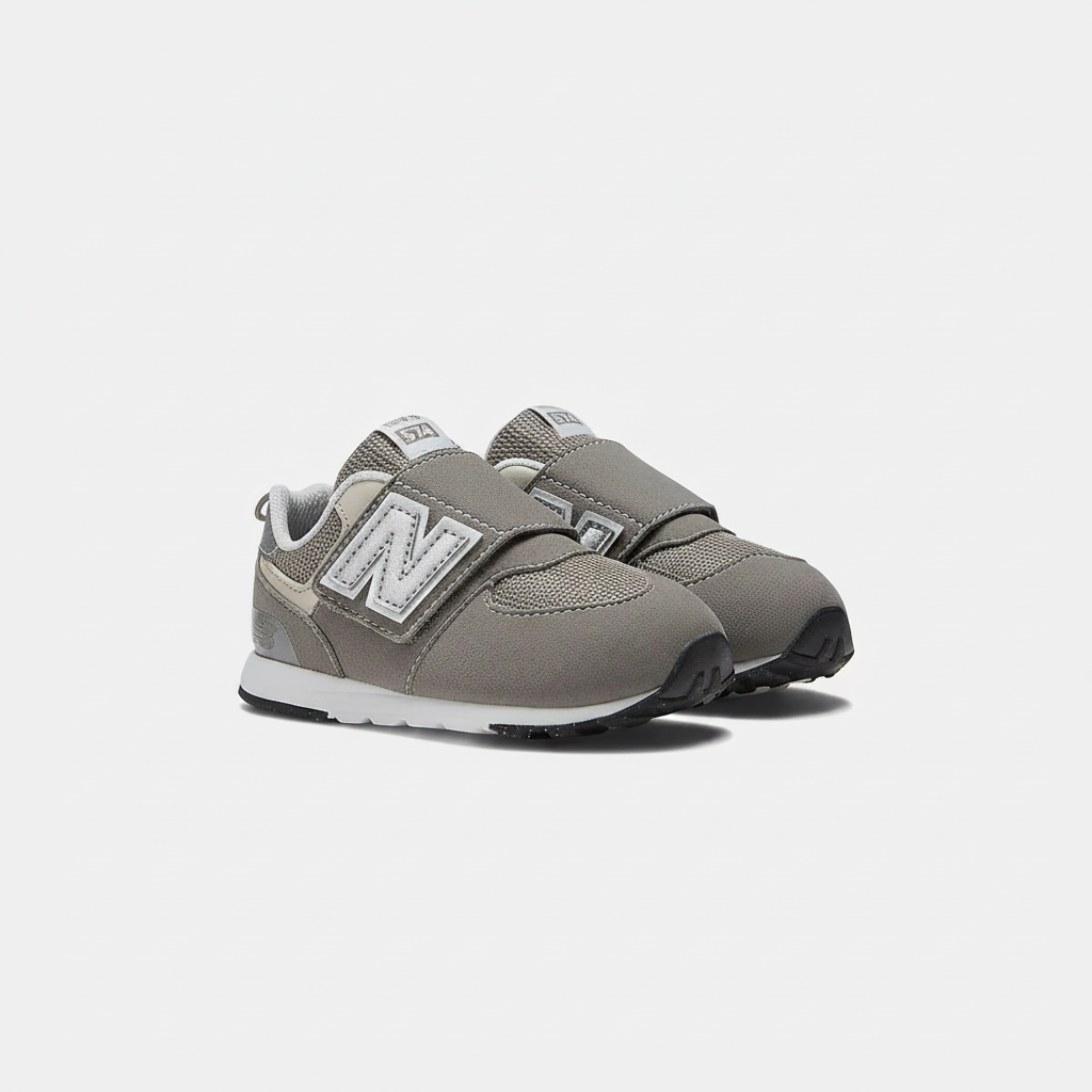 Grey New Balance 574 children's sneakers with white 'N' logo, silver accents, and hook & loop straps.