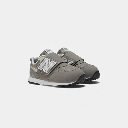 Grey New Balance 574 children's sneakers with white 'N' logo, silver accents, and hook & loop straps.