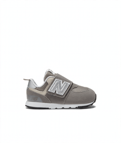 Grey New Balance 574 children's sneaker featuring a silver N logo, hook-and-loop strap, and white midsole.