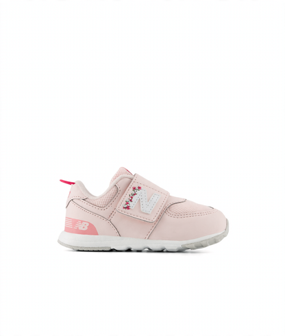 Pink New Balance children's sneaker with hook and loop closure, white 'N' logo with floral embroidery, and a pink pull tab.