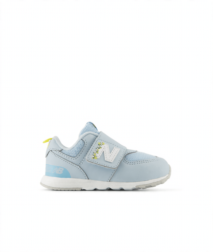 Light blue New Balance 574 children's sneaker with hook & loop closure, white N logo with floral details, and yellow heel tab.