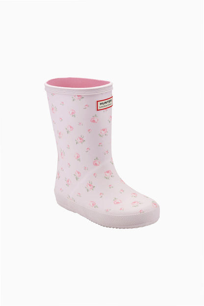 Light pink Hunter x LoveShackFancy kids' rain boot with a pink rose floral pattern, pink knit lining, and a red Hunter logo.