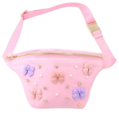 Pink children's fanny pack with a gold zipper, adjustable strap, and decorated with pastel bows, pearls, and rhinestones.