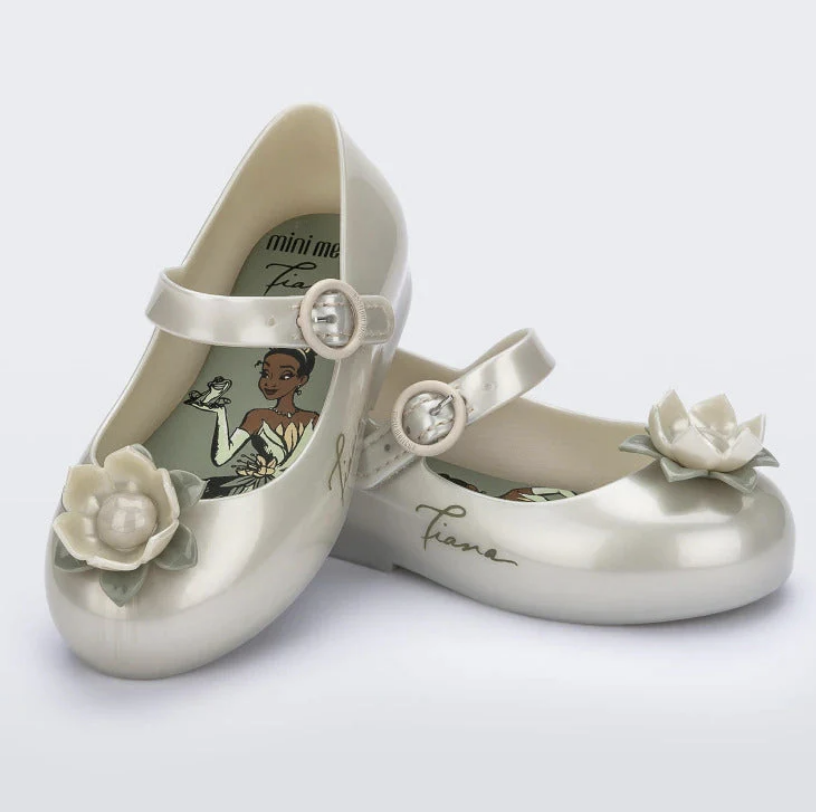 Pearlescent off-white children's Mary Jane flats with a strap, a 3D lotus flower on the toe, and Princess Tiana illustration on the insole.