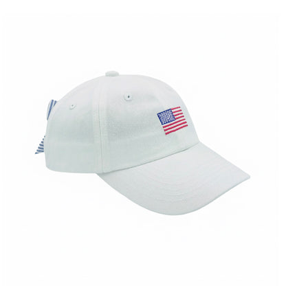 White baseball hat with an embroidered American flag on the front and a blue and white striped bow on the back.