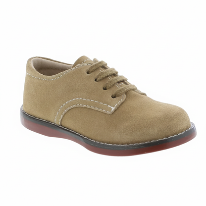 Children's tan suede derby shoe with white contrast stitching, matching laces, and a red sole.