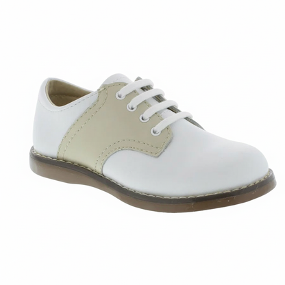 Children's white and tan saddle shoe with white laces and a brown sole, viewed from the side.