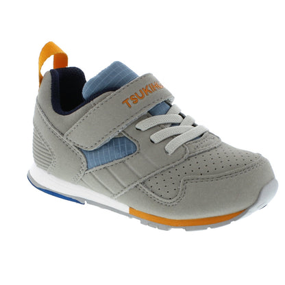 Grey children's athletic shoe with blue and orange accents, featuring a Tsukihoshi branded velcro strap, elastic laces, and a heel pull tab.