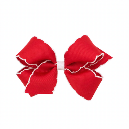 A vibrant red grosgrain hair bow with scalloped white moonstitch edges and a contrasting white center wrap.