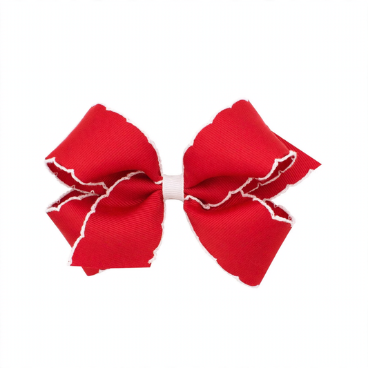 A vibrant red grosgrain hair bow with scalloped white moonstitch edges and a contrasting white center wrap.