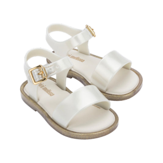 Pair of shiny white Mini Melissa baby sandals with gold glitter soles and gold buckles.