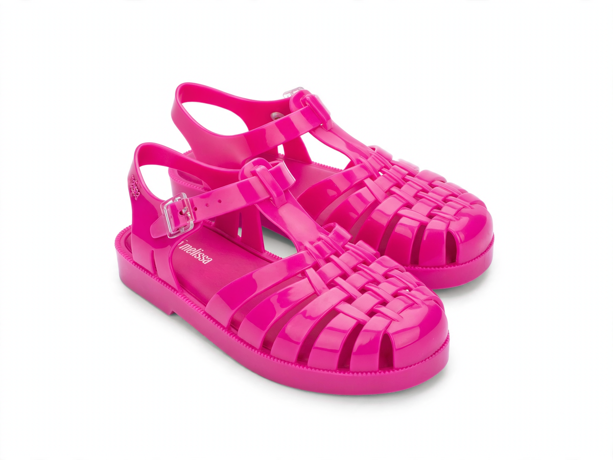 Bright pink shiny jelly sandals for kids with a woven toe, ankle strap, and buckle closure.