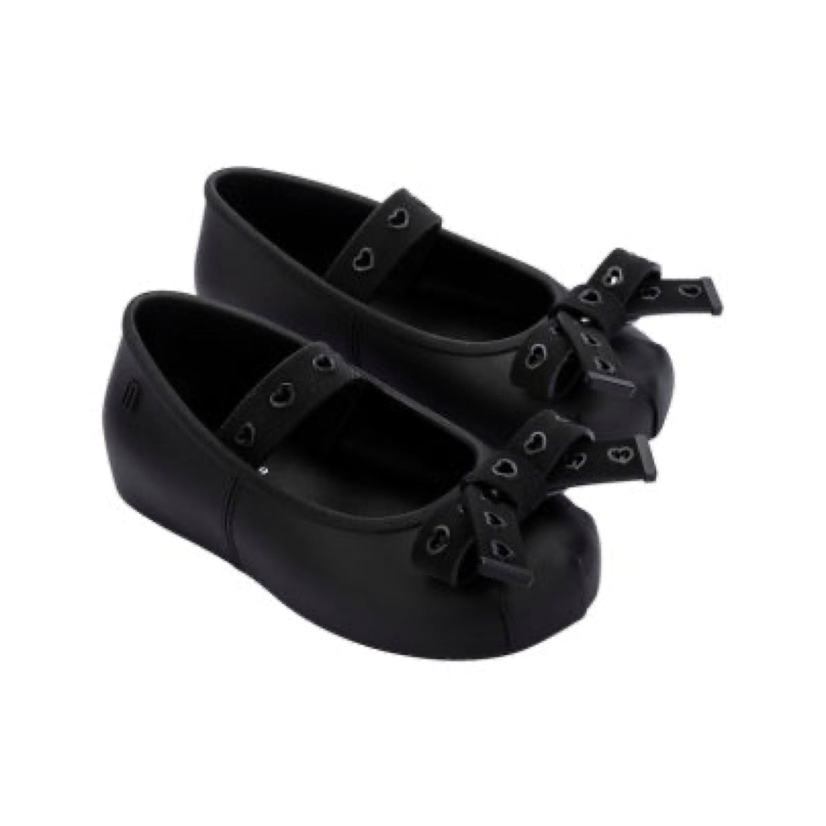Two pairs of black matte children's Mary Jane flats with heart-cutout straps and bows on the toes.