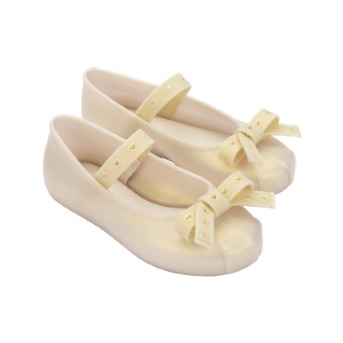 Pair of light beige jelly Mary Jane flats with heart-perforated straps and bows on the toes.