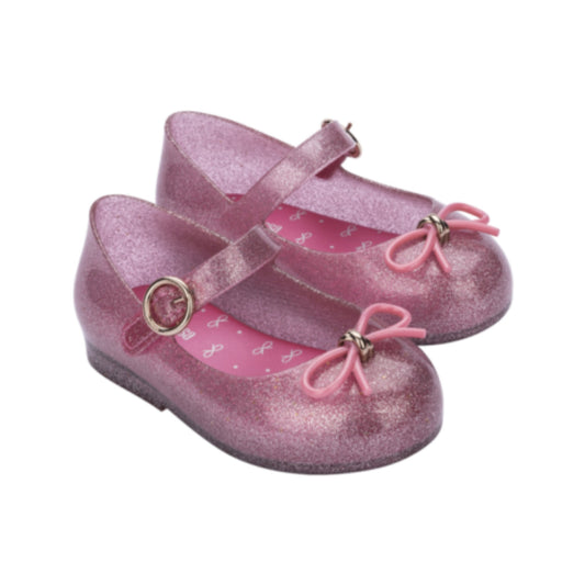 Pair of glittery pink children's Mary Jane flats with buckle straps, pink bows with gold accents, and patterned pink insoles.