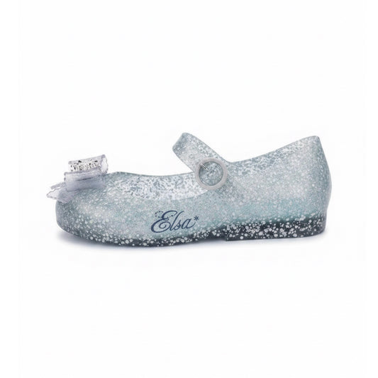 Glittery translucent light blue Mary Jane flat with a clear bow on the toe, a buckle strap, and 'Elsa*' written on the side.