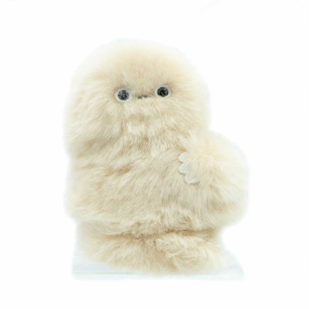 A fluffy cream-colored robotic plush toy with large black eyes and a small stitched nose, standing upright on a clear display base against a light blue background.