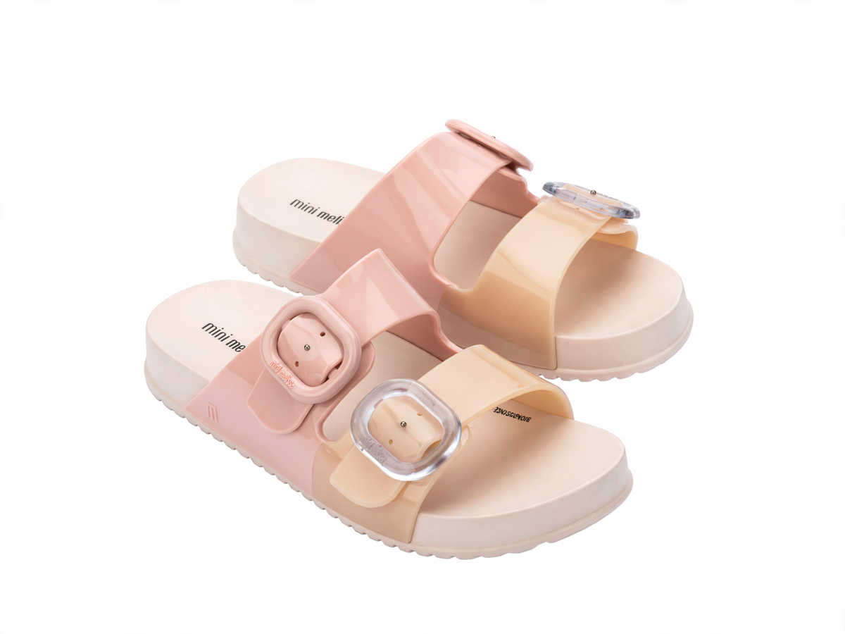 Children's Mini Melissa Cozy Slide sandals in pink and beige, featuring two wide straps with clear adjustable buckles and a thick sole.