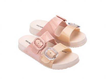 Children's Mini Melissa Cozy Slide sandals in pink and beige, featuring two wide straps with clear adjustable buckles and a thick sole.