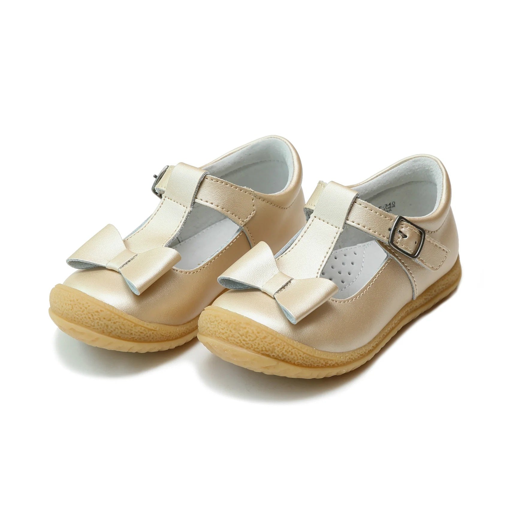 Pair of L'Amour Emma children's gold metallic T-strap shoes with a decorative bow on the toe and a textured rubber sole.