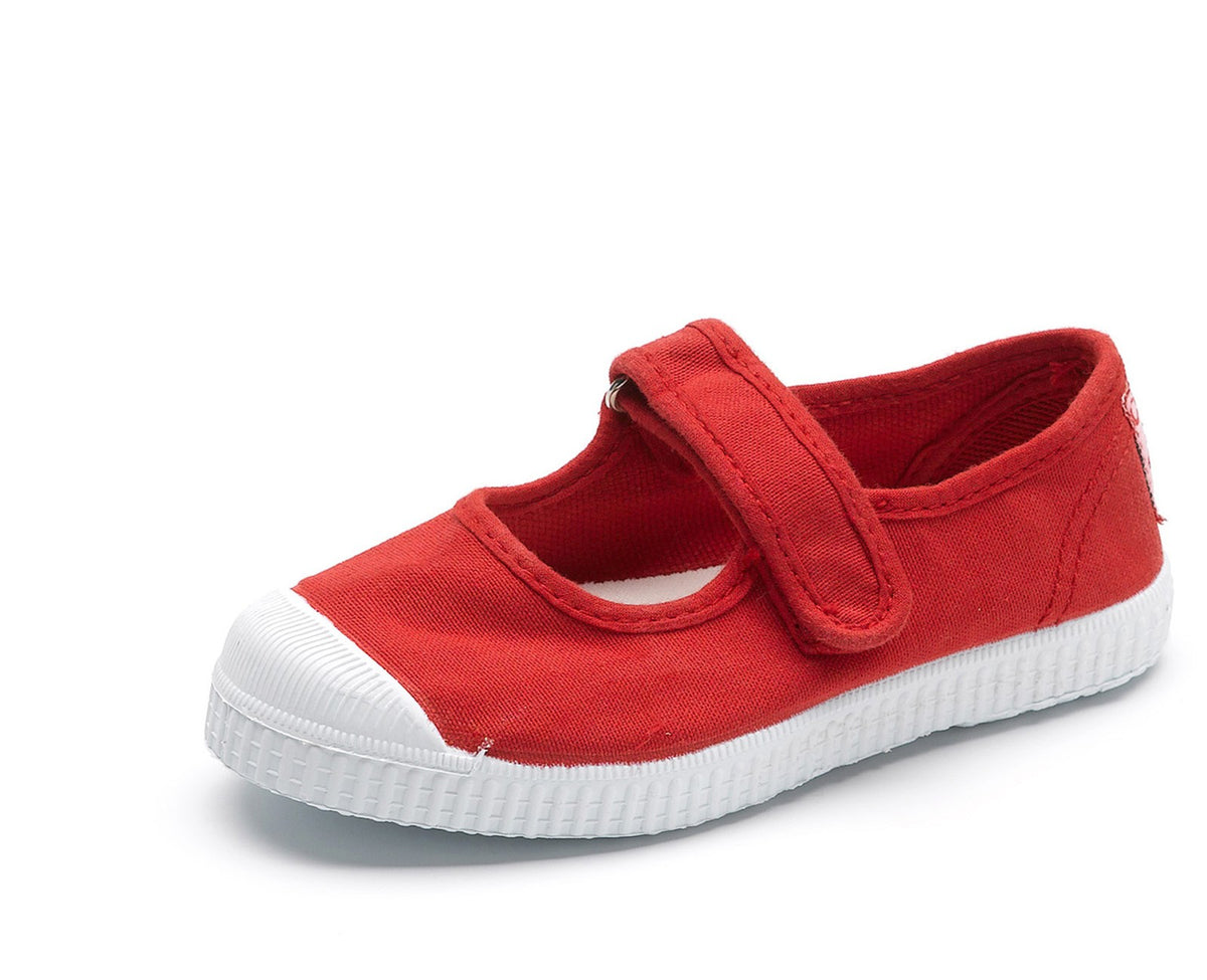 Red canvas children's Mary Jane shoe with a white ribbed rubber toe cap and sole, featuring a single Velcro strap.