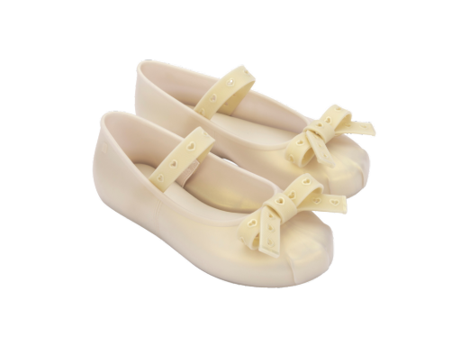 Pair of light beige jelly Mary Jane flats with heart-perforated straps and bows on the toes.