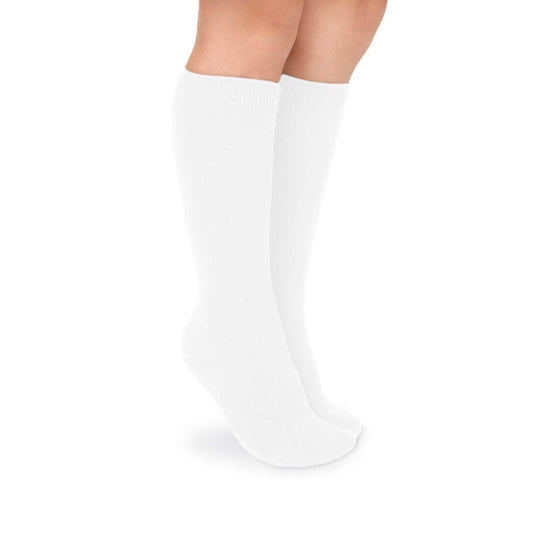 Child's legs wearing smooth white cotton knee socks with ribbed cuffs, standing on a white background.