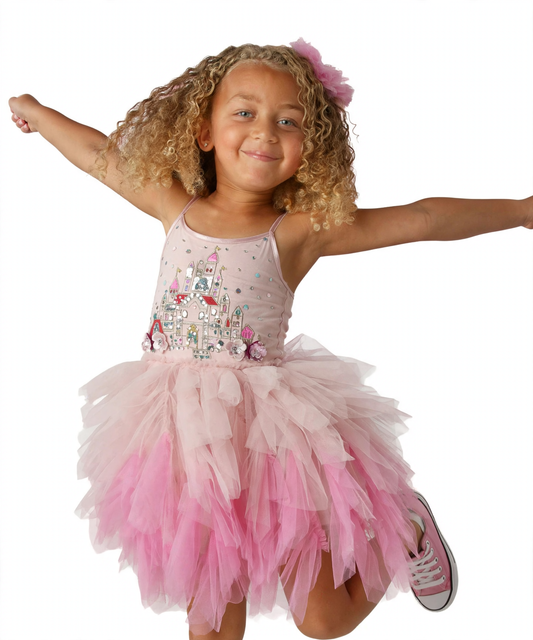 A young girl with curly blonde hair wearing a pink tutu dress with a castle embellishment on the bodice, posing with her arms outstretched against a white background.