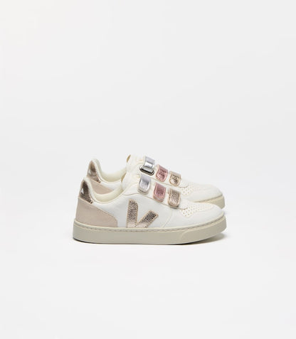 White leather children's sneakers with metallic gold V-logo, light beige accents, and three metallic silver, pink, and gold velcro straps.