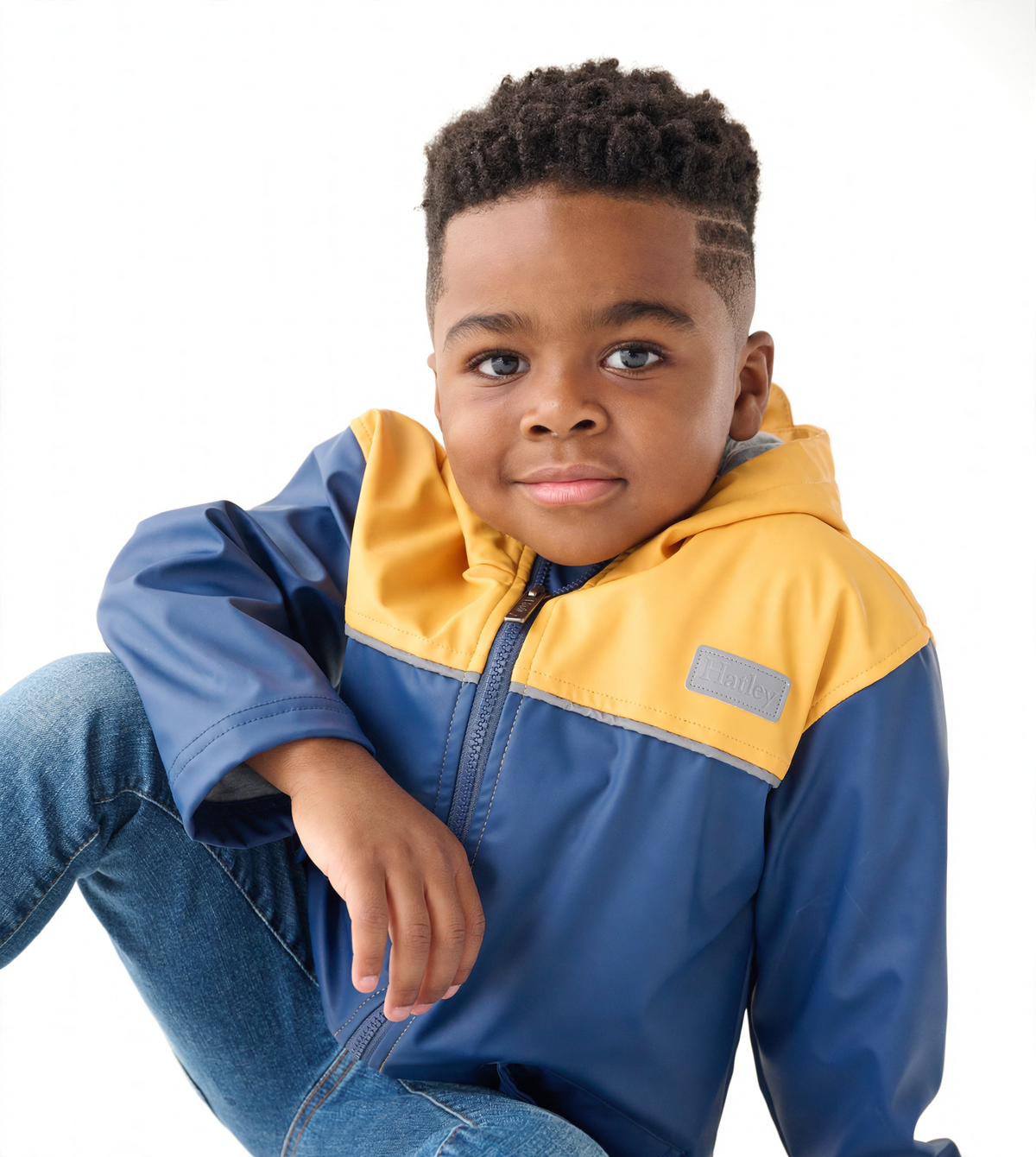 Yellow and navy zip-up rain jacket with a hood, worn by a child, featuring a smooth, waterproof material.
